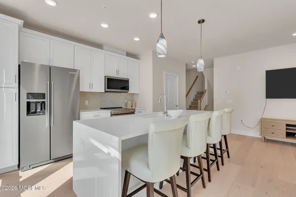 a large kitchen with stainless steel appliances kitchen island granite countertop a table chairs microwave and sink
