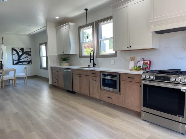 a kitchen with stainless steel appliances a stove a sink cabinets and wooden floor