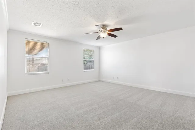 an empty room with windows and fan