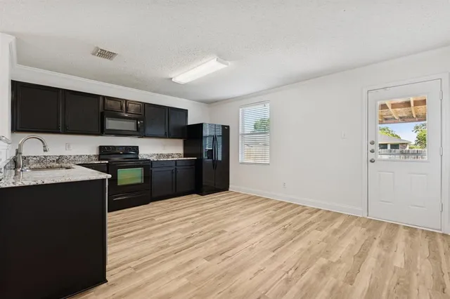 a kitchen with granite countertop a refrigerator stove top oven and sink