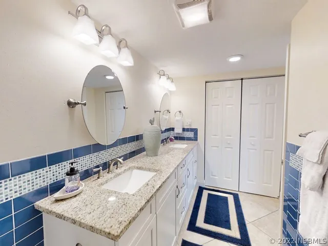 a bathroom with a granite countertop double vanity sink and a mirror