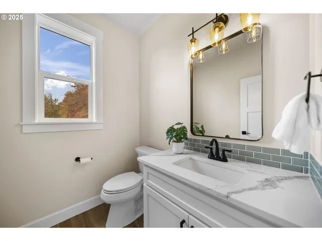 a bathroom with a granite countertop toilet a sink and mirror