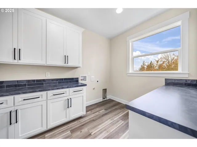 a kitchen with granite countertop white cabinets and a wooden floor
