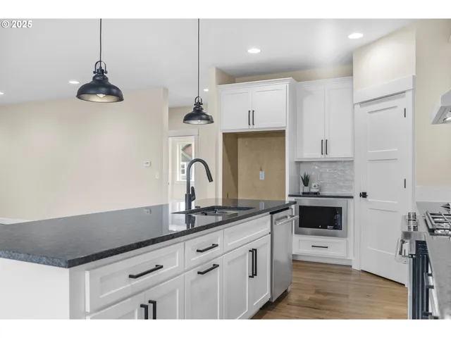 a kitchen with granite countertop a sink a stove and cabinets