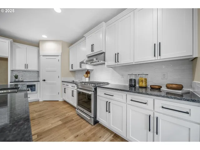 a kitchen with granite countertop white cabinets and stainless steel appliances