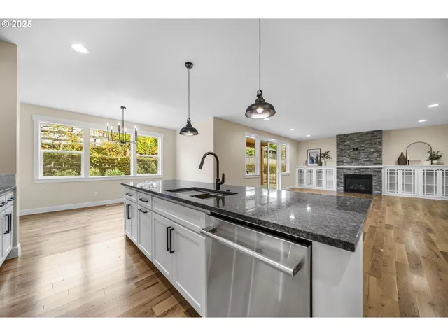 a kitchen with stainless steel appliances granite countertop a sink a stove and a wooden floors