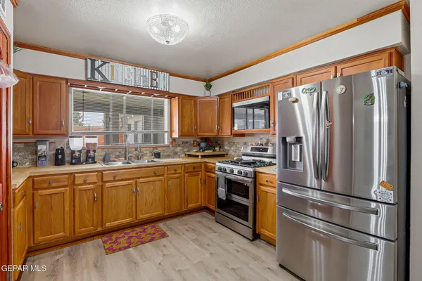 a kitchen with stainless steel appliances granite countertop a refrigerator a stove and a sink