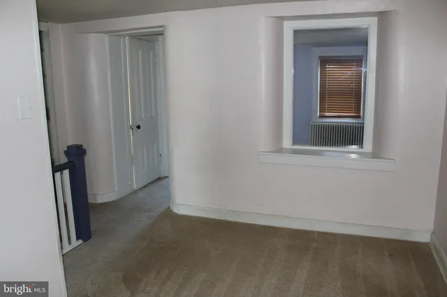 a view of an empty room with closet and mirror