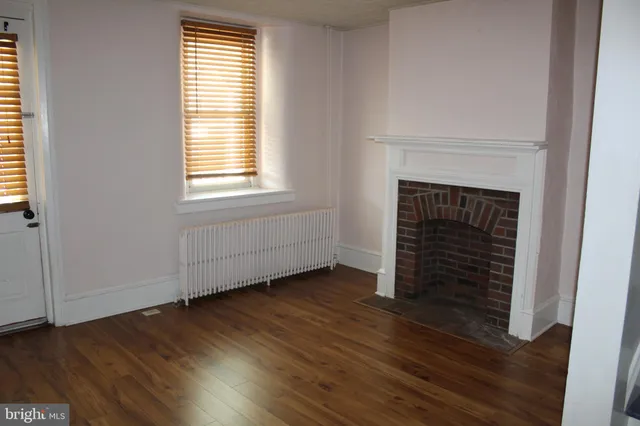 an empty room with wooden floor fireplace and windows