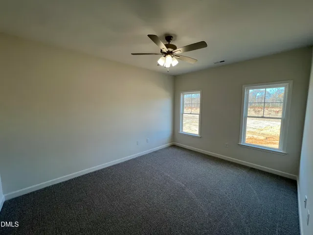 an empty room with a chandelier fan and a window
