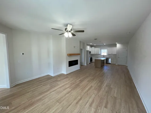 a view of an empty room with wooden floor and a fireplace