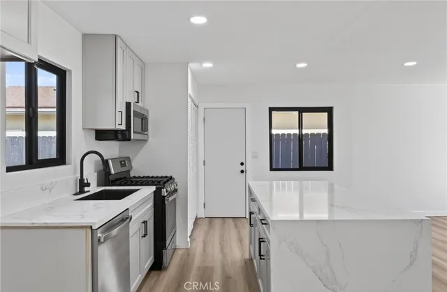a kitchen with a sink and a stove top oven with wooden floor