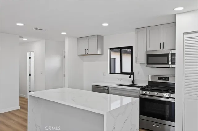 a kitchen with stainless steel appliances a stove refrigerator sink and cabinets