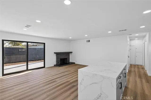a view of an empty room with wooden floor and a fireplace