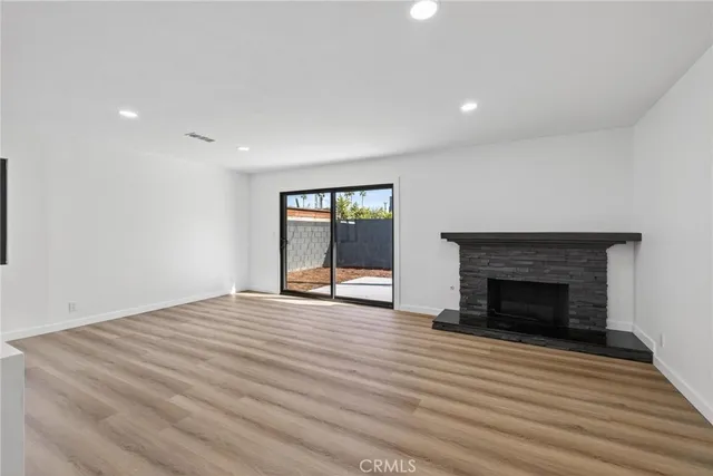 an empty room with wooden floor fireplace and windows