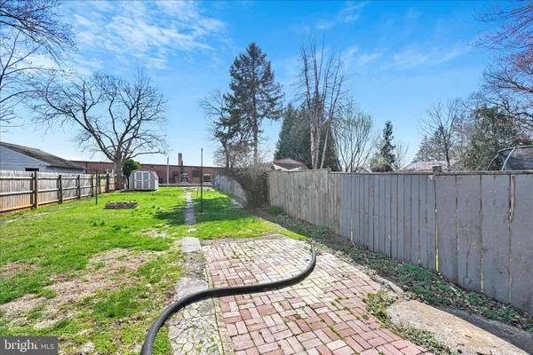 a view of a backyard with large trees and wooden fence
