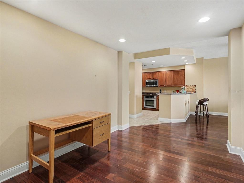 611 Riviera Dunes Way, Unit 102 Palmetto, FL 34221 - Photo 17 of 34 a room with wooden floor and a kitchen