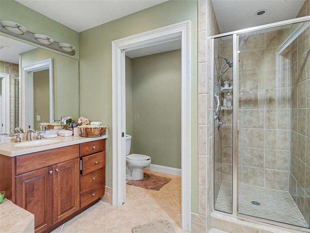 611 Riviera Dunes Way, Unit 102 Palmetto, FL 34221 - Photo 20 of 34 a bathroom with a granite countertop sink toilet and shower