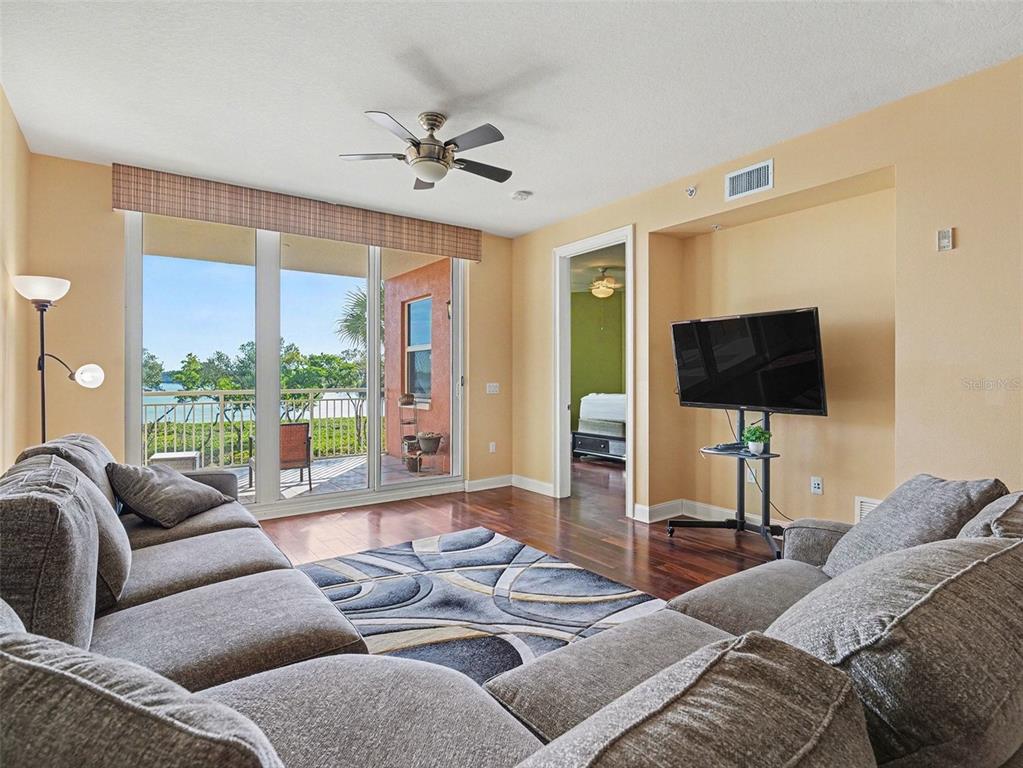611 Riviera Dunes Way, Unit 102 Palmetto, FL 34221 - Photo 2 of 16 a living room with furniture a large window and a flat screen tv