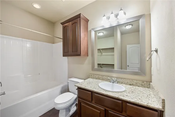 a bathroom with a granite countertop sink a toilet and shower