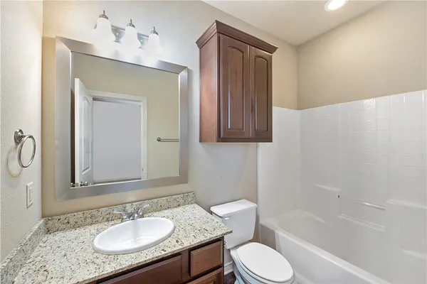 a bathroom with a granite countertop sink toilet a mirror and bathtub