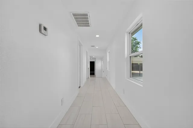 a view of a hallway with wooden floor and a bathroom