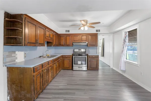 a kitchen with stainless steel appliances a sink a stove top oven a refrigerator cabinets and wooden floor