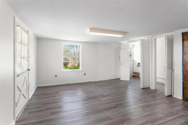 a view of an empty room with wooden floor and a window