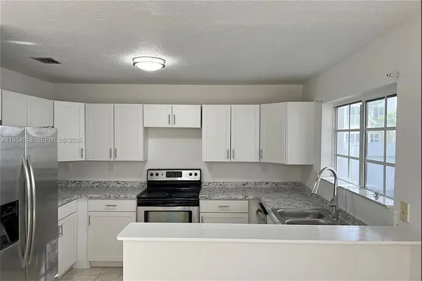 a kitchen with stainless steel appliances granite countertop a stove a sink and a refrigerator