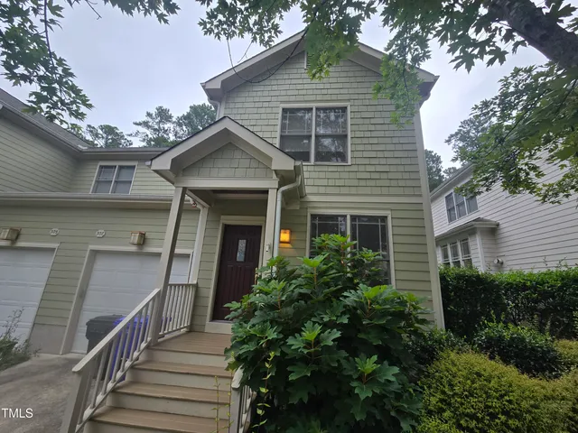 a front view of a house with wooden stairs and potted plants