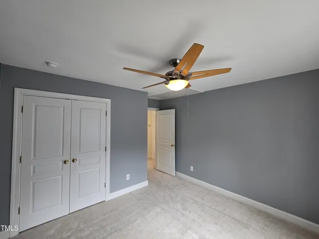 an empty room with a ceiling fan and window
