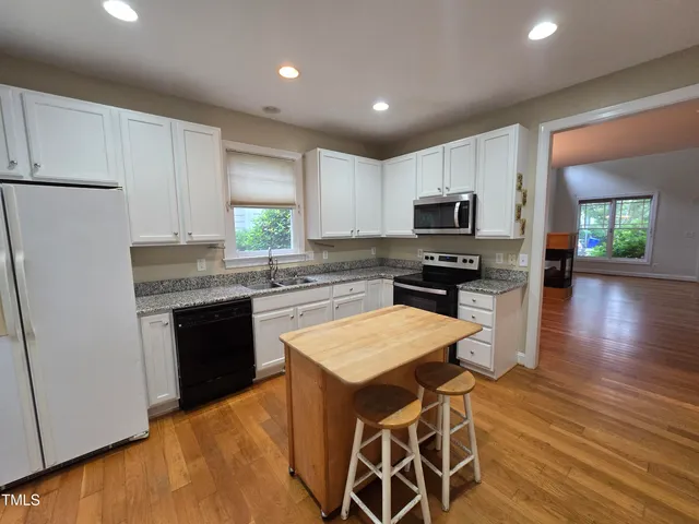 a kitchen with granite countertop a refrigerator stove top oven and sink
