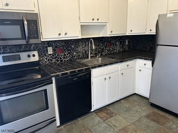 a kitchen with white cabinets and black appliances