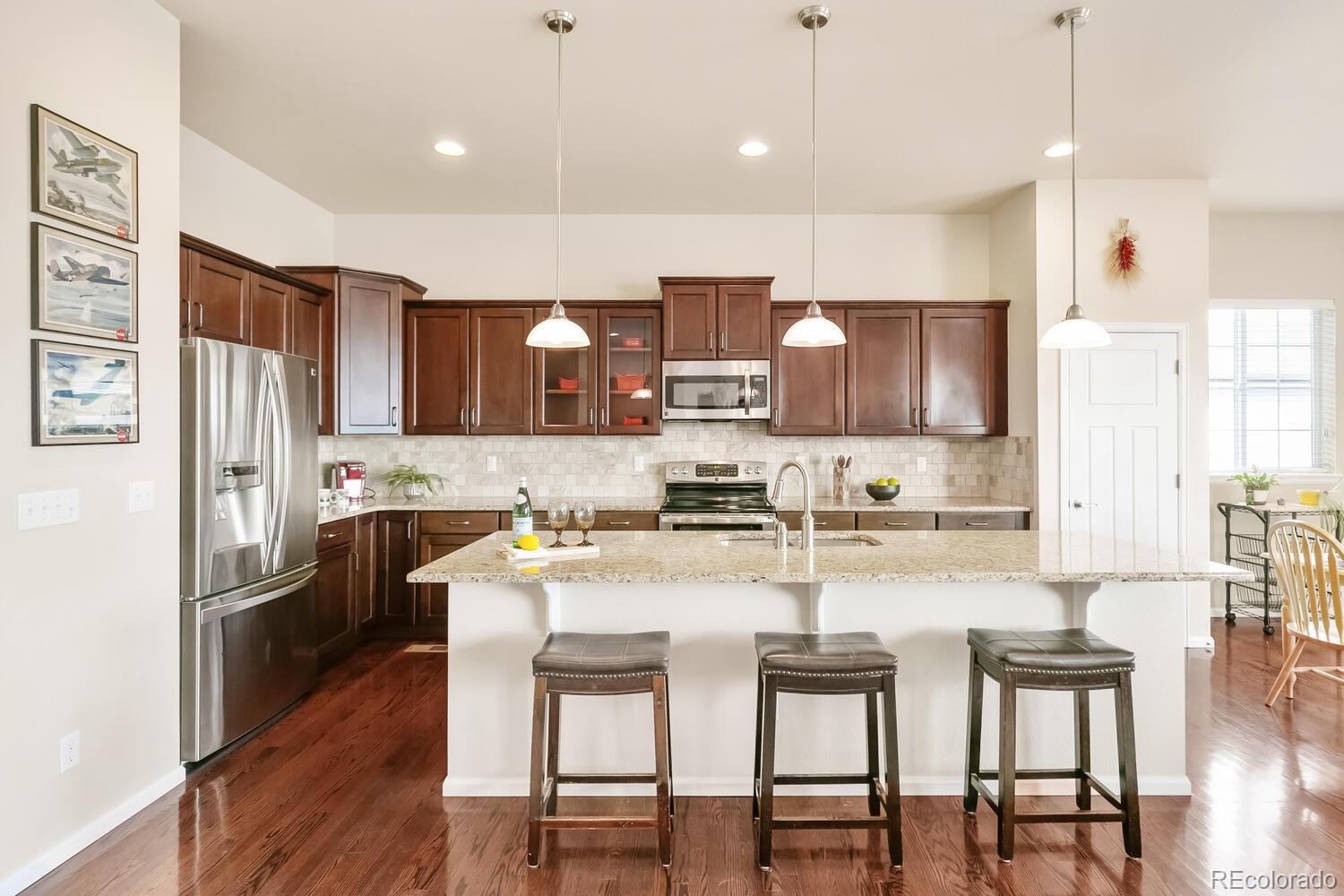 6797 East Phillips Place Centennial, CO 80112 - Photo 1 of 40 a kitchen with refrigerator a sink and chairs