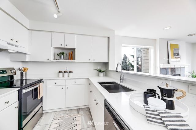 a kitchen with a refrigerator a stove a sink and white cabinets