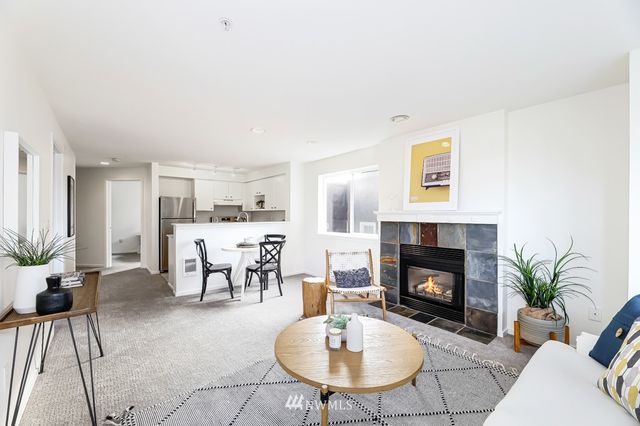 a kitchen with stainless steel appliances kitchen island granite countertop a dining table chairs and a refrigerator