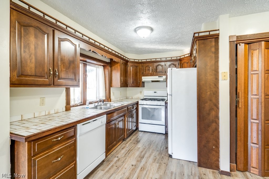 3693 Fishcreek Road Stow, OH 44224 - Photo 5 of 23 Kitchen with a textured ceiling, white appliances, tile counters, and light hardwood / wood-style flooring