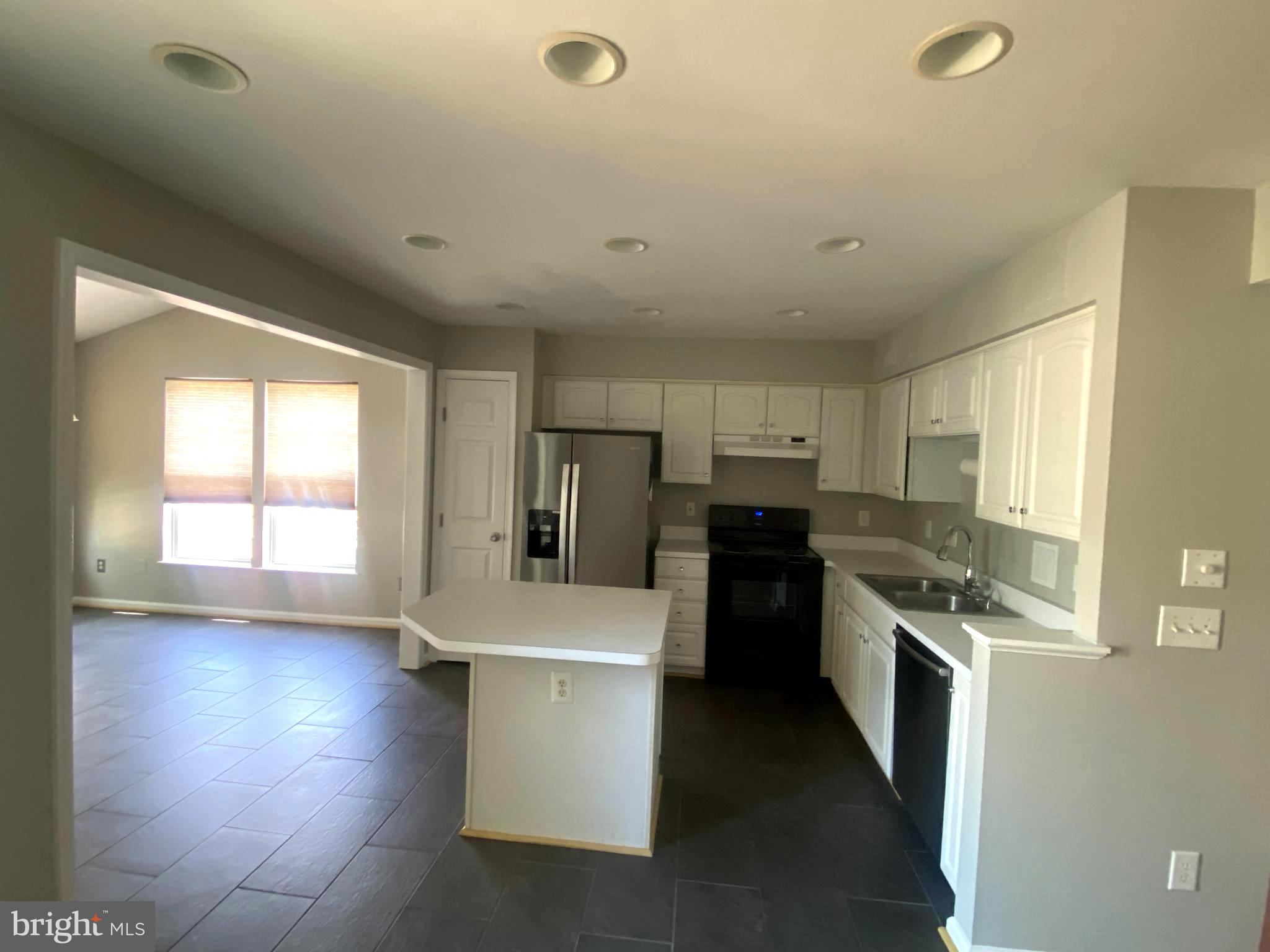 19958 Fieldgrass Square Ashburn, VA 20147 - Photo 4 of 14 a kitchen with stainless steel appliances a stove a sink a refrigerator white cabinets and wooden floor