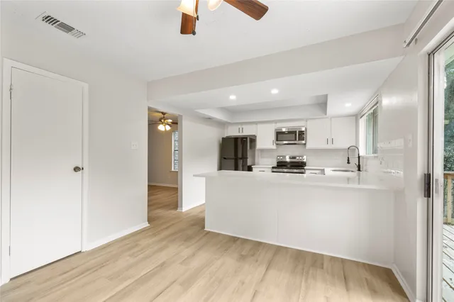 a living room with stainless steel appliances kitchen island hardwood floor and a view of kitchen