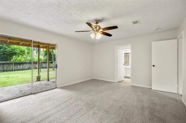 a view of an empty room with a window and a ceiling fan