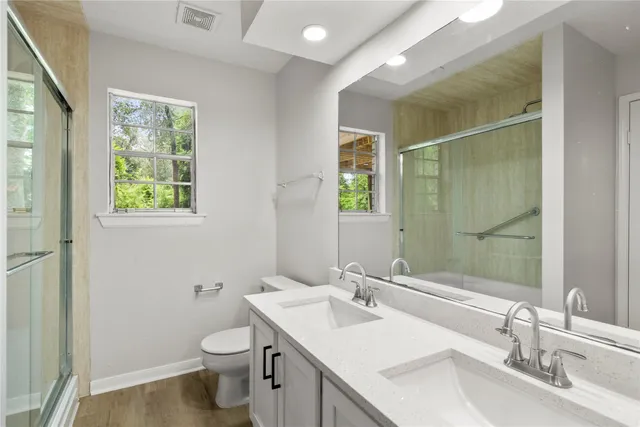 a bathroom with 2 sink toilet and a mirror