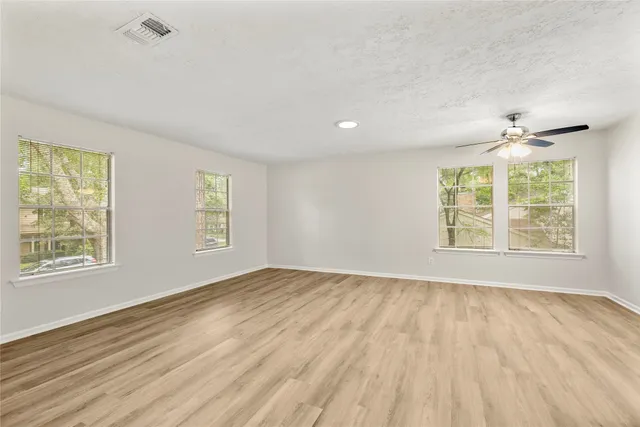 a view of an empty room with a window and wooden floor