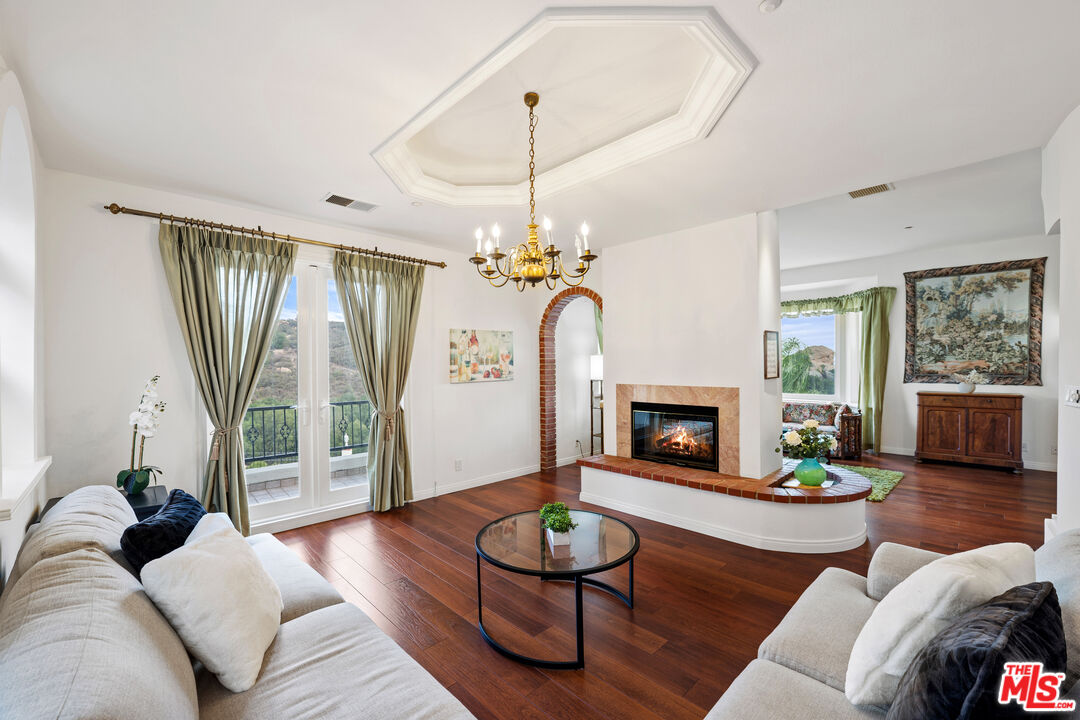 7449 Studio Road West Hills, CA 91304 - Photo 20 of 33 a living room with furniture a fireplace and a chandelier