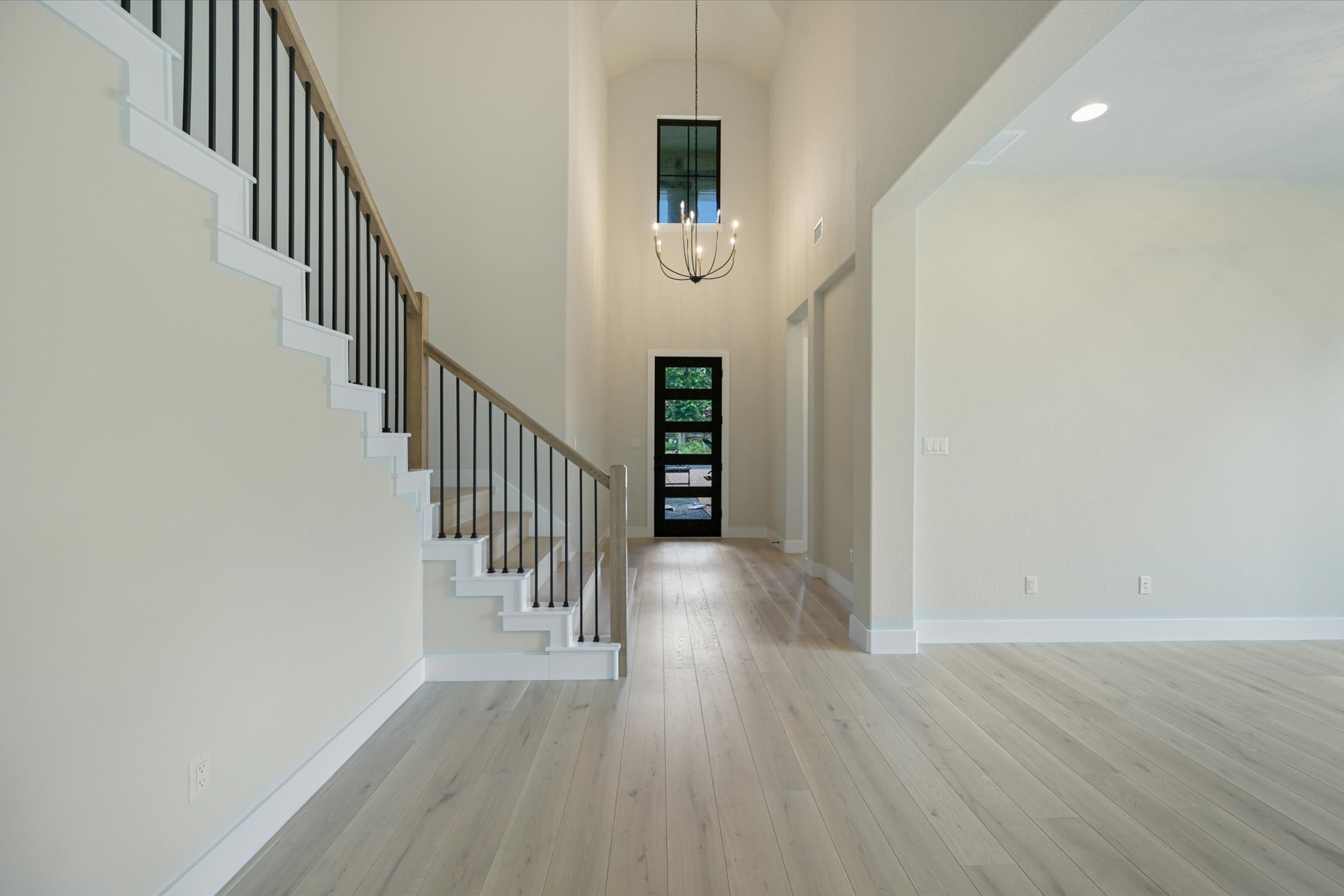 913 Presa Arriba Road Austin, TX 78733 - Photo 2 of 30 A grand entrance with soaring ceilings, light wood floors, and an elegant staircase.