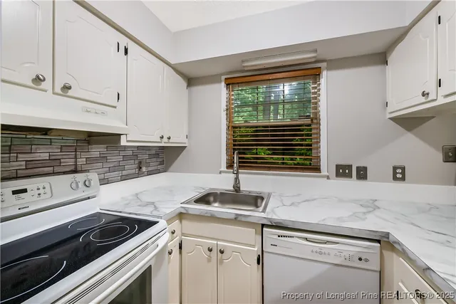 a kitchen with granite countertop white cabinets and white appliances