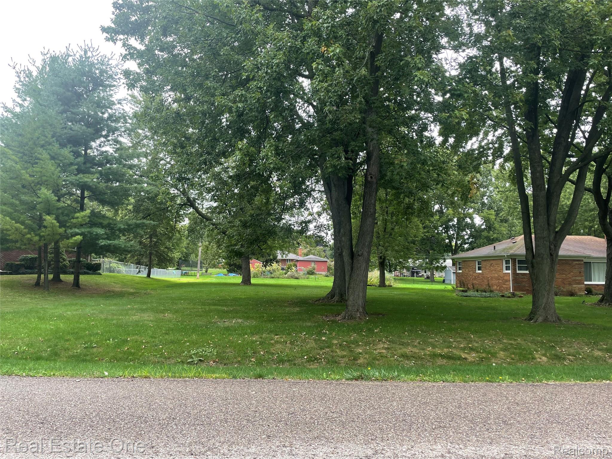 6346 Donaldson Road Troy, MI 48085 - Photo 8 of 8 Expansive green space featuring established trees and a distant brick-clad structure