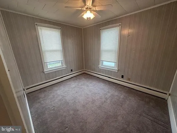 an empty room with windows and fan