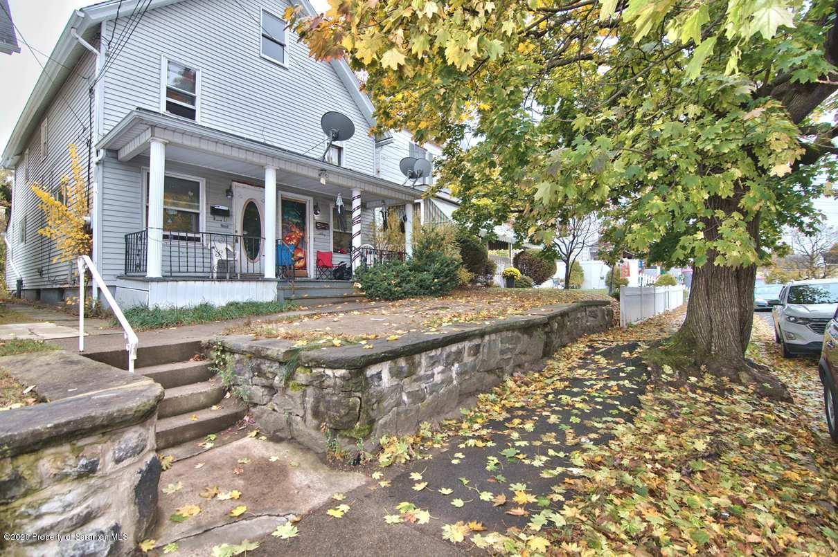 a front view of a house with a tree