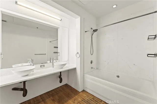 a bathroom with a tub shower sink and mirror