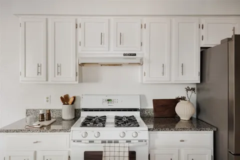 a kitchen with white cabinets and appliances
